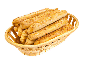 Bunch of bread sticks with sesame seeds in a wicker kitchen basket. Isolated on white background