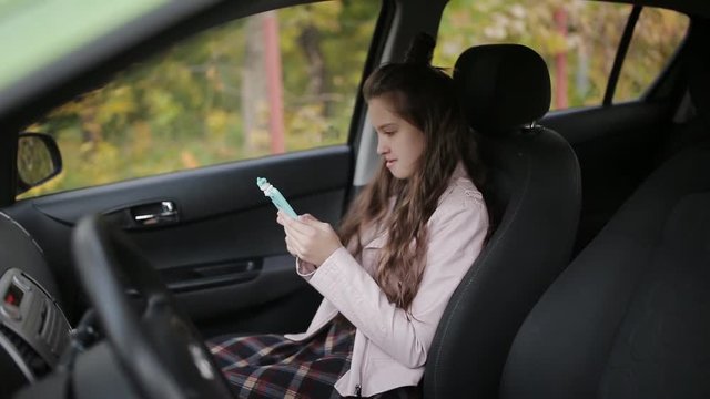 A young woman with her teenage daughter is spending time together. Mom gets a car, and daughter uses a smartphone