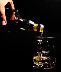 Glass of whiskey with liquid and ice cubes