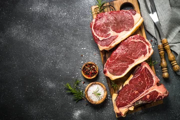 Abwaschbare Fototapete Steakhouse Rindersteak aus rohem Fleisch auf schwarzer Draufsicht.