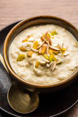 Sweet Rabdi or Lachha Rabri or basundi, made with pure milk garnished with dry fruits. Served in a bowl over moody background. Selective focus