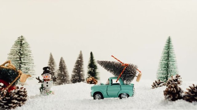 Toy cars carrying Christmas tree in snowy and winter landscape