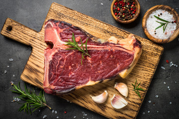T-bone beef steak on black with spices.
