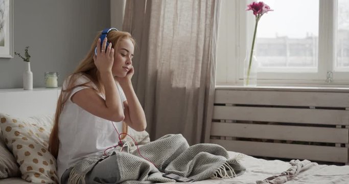 Young Woman Using Smart Phone Lying On Bed