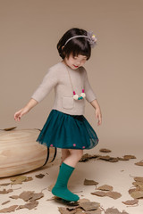 Little pretty Asian girl sitting in an autumn background.