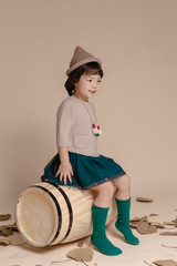 Little pretty Asian girl sitting in an autumn background.