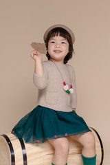 Little pretty Asian girl sitting in an autumn background.