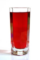 glass with berry red ruby juice on white background with reflection on glass table