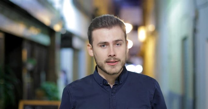 Front View Of A Happy Man Talking At Camera In The Night In The Street