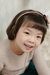 Little pretty Asian girl standing in a normal indoor life background.