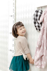 Little pretty Asian girl standing in a normal indoor life background.