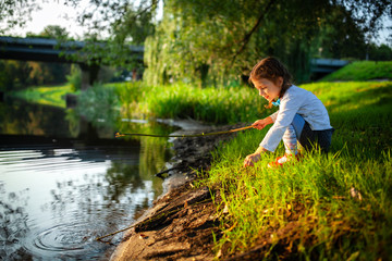 The traveler with a photo camera in his hands. Girl travels with the camera. The traveler on the riverbank photographes the sunset. Sunset on the river or lake, sea, ocean.