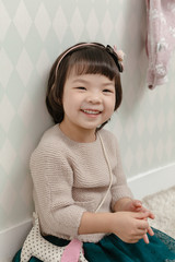 Little pretty Asian girl standing in a normal indoor life background.