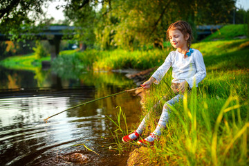 Little girl sprinkles water on the river bank