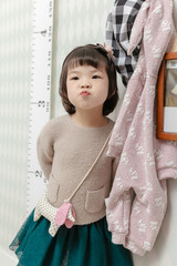 Little pretty Asian girl standing in a normal indoor life background.