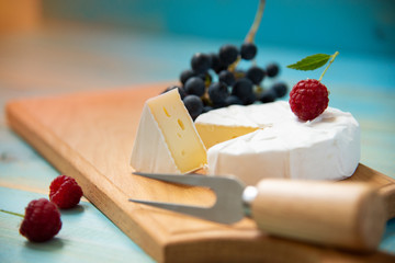 cheese camembert with raspberries and grapes on table