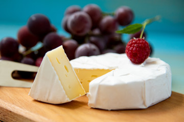 cheese camembert with raspberries and grapes on table