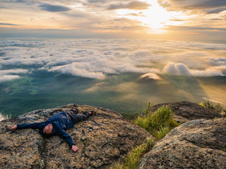 Trekker Lay down on the cliff with Beautiful Sunrise and sea of mist in the morning on Khao Luang...