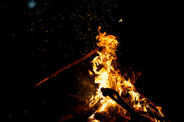 Burning woods with firesparks, flame and smoke. Strange weird odd elemental fiery figures on black background. Coal and ash. Abstract shapes at night. Bonfire outdoor on nature. Strenght of element.