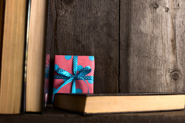 Obraz premium A gift hidden on a wooden shelf behind the books.