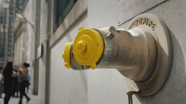Yellow Fire hydrant in the wall of a building on Wall Street in New York