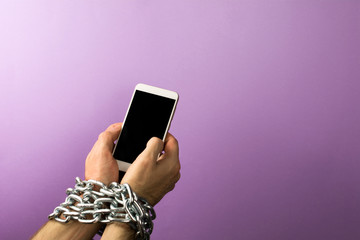  iron chain that ties together hand and smart phone. Addiction to smartphone or mobile devices concept.