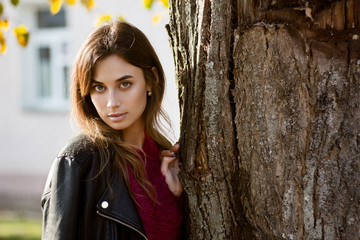 Young woman at fall near tree, looking in camera, shallow depth of field