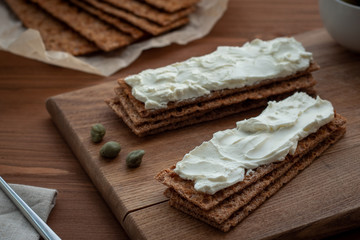 Crisp bread and ricotta on cutting board. 