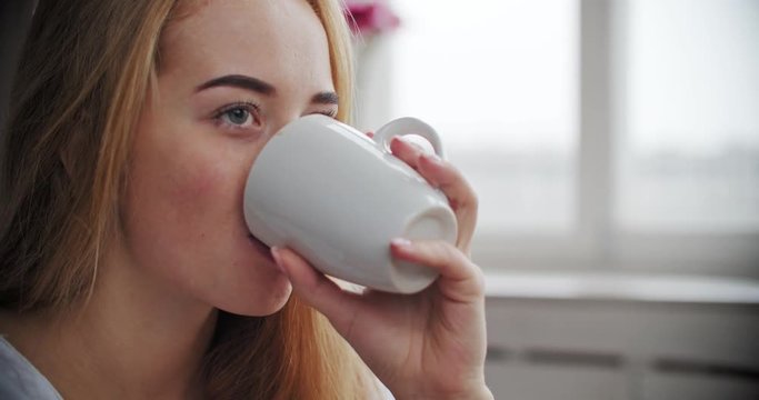 woman drinking hot tea or coffee in morning light