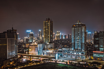 Fototapeta na wymiar Illuminated high-rises line the horizon in downtown Jakarta Indonesia at night.