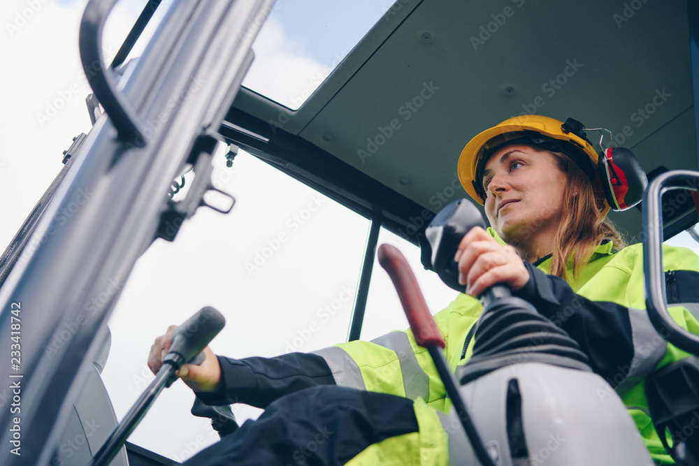 Wall mural low angle view of woman driving heavy equipment