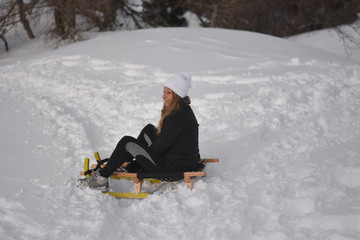 Young woman has fun on sled and snow