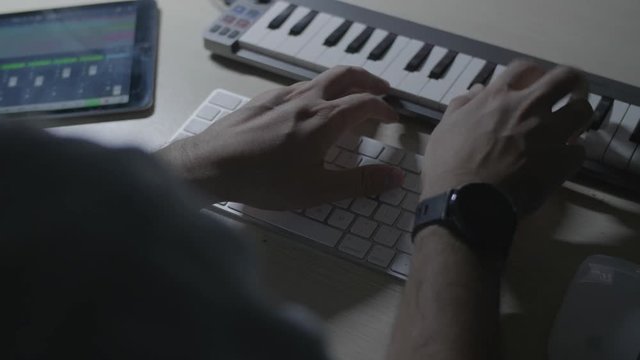 Close up on producer musician hands playing a melody riff on a MIDI keyboard