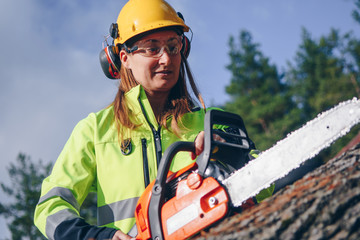 Female in safety clothing operating chain saw