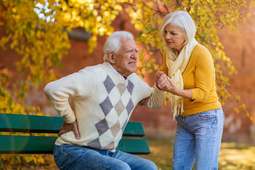 Senior woman helping senior man who has a back pain