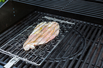 Rohes Fischfilet in einem Fischgrillwender grillt auf einem Gas Grill