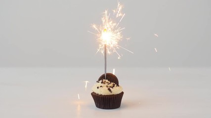 Delicious birthday cupcake with burning sparkler on white table - Powered by Adobe