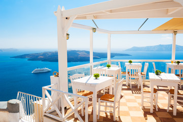 Cafe on the terrace overlooking the sea. Santorini island, Greece - obrazy, fototapety, plakaty