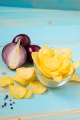 Obraz na płótnie Canvas Potato chips in bowl on a blue wooden background