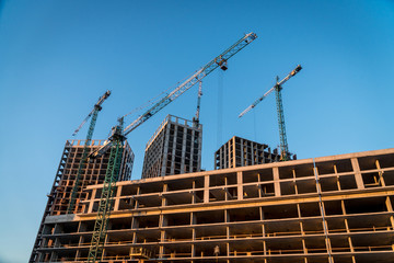 Construction site with reinforced concrete and brick buildings and cranes.