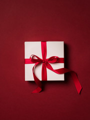 Top view of gift box with red ribbon over red background