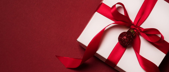 Top view of gift box with red ribbon over red background