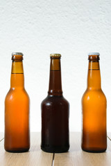 Cold beer bottle without label on wooden table back-lit isolated on white background