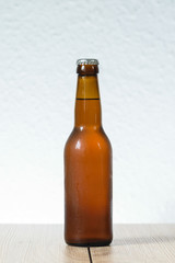 Cold beer bottle without label on wooden table back-lit isolated on white background