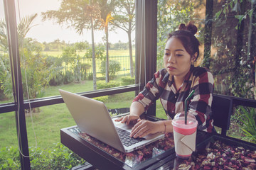 Young asia woman sitting alone at coffee shop working on a laptop