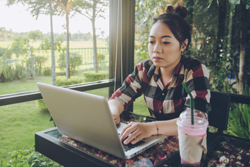 Young asia woman sitting alone at coffee shop working on a laptop