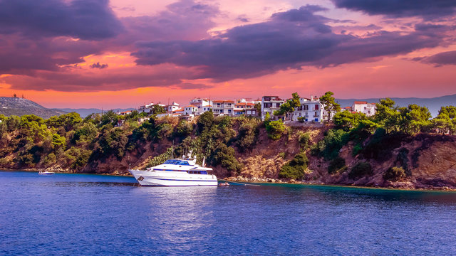 Sunset over Skiathos town, Greece. Luxury yacht in the bay of Skiathos, near the harbour