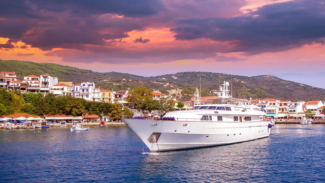 Sunset over Skiathos town, Greece. Luxury yacht in the bay of Skiathos, near the harbour