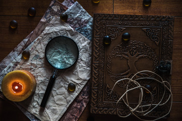 beautiful vintage background with ancient book, old maps, a candle, a magnifying glass and some stones