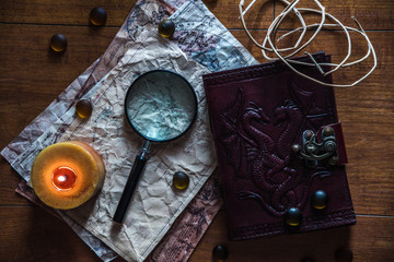 beautiful vintage background with ancient book, old maps, a candle, a magnifying glass and some stones